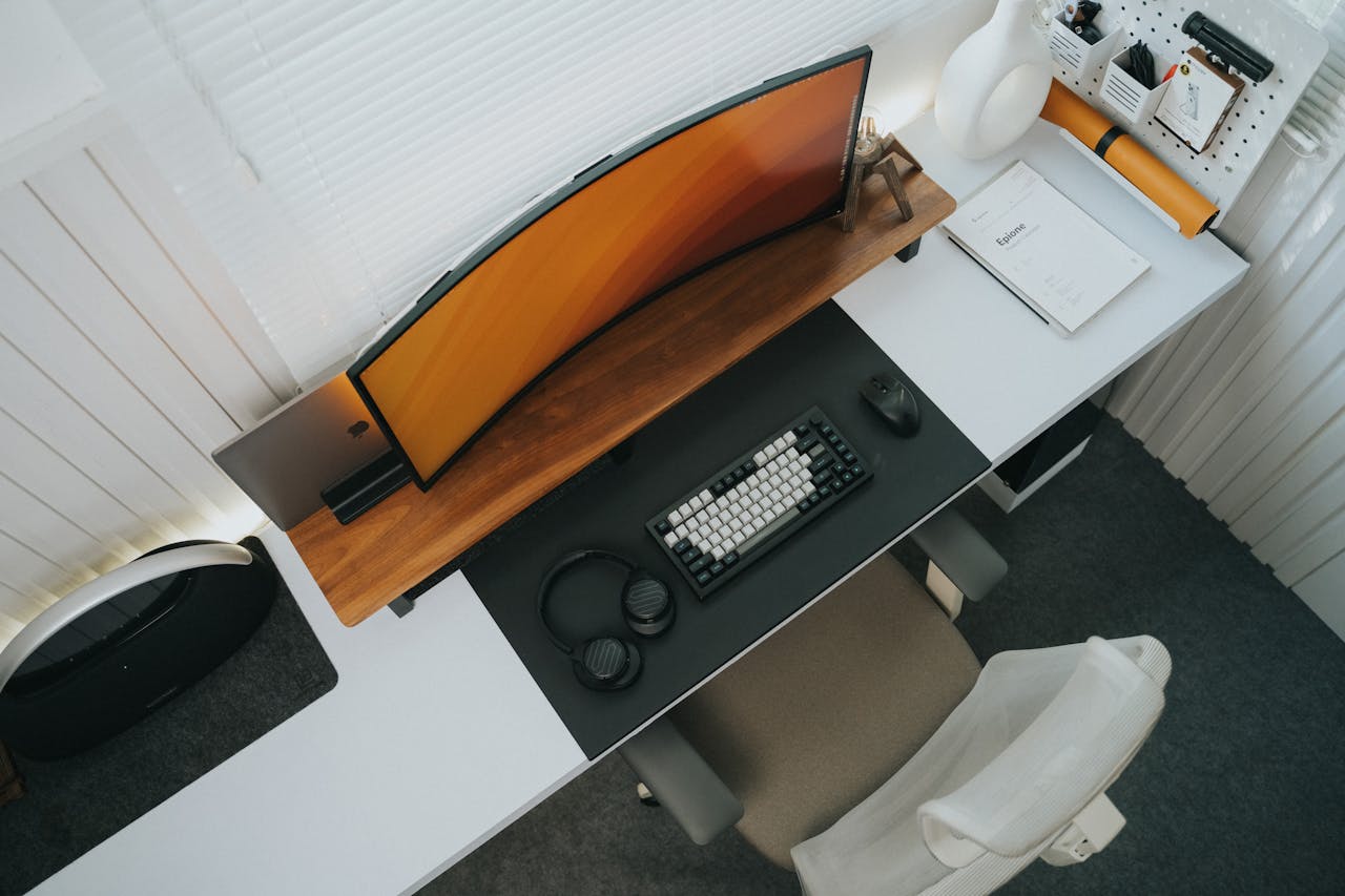 home-services-01 Top view of a stylish modern office desk setup featuring a curved monitor and keyboard.