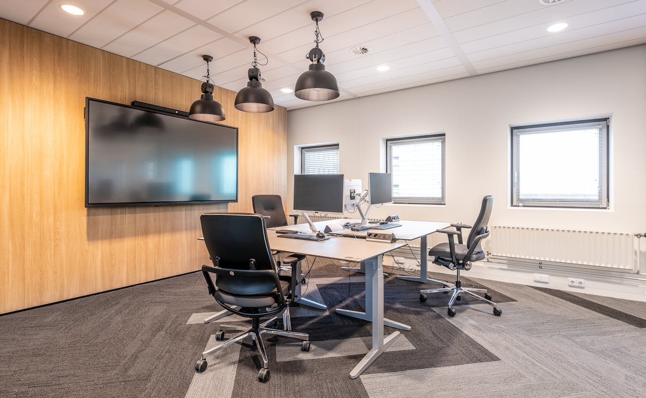 Spacious, well-lit office conference room featuring modern computers and a large screen display for presentations.