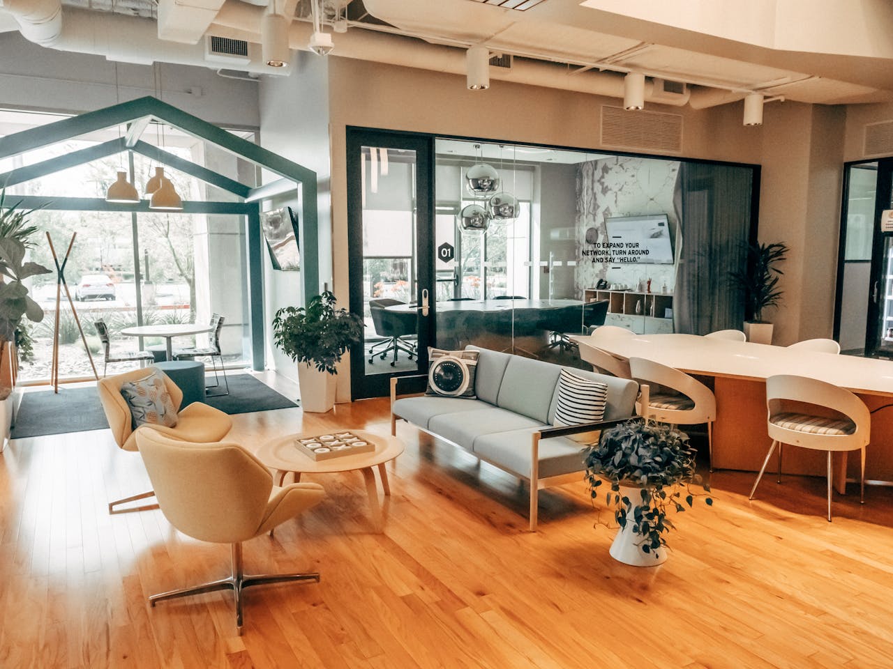 home-services-004 A stylish open office space featuring modern furniture with a relaxed lounge area and glass partitions.